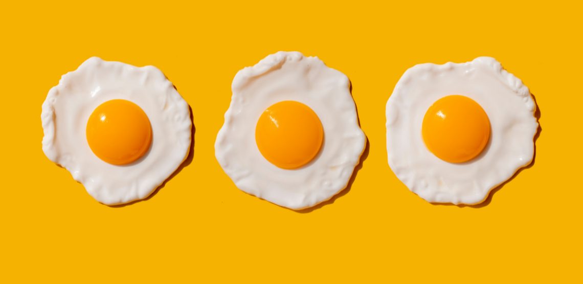 Three fried eggs on a yellow background