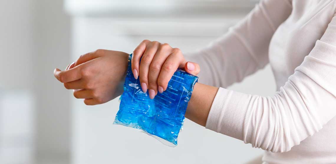 A person pressing an ice pack to their wrist.